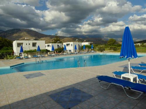 a large swimming pool with blue umbrellas and chairs at KALIVAKI in Georgioupolis