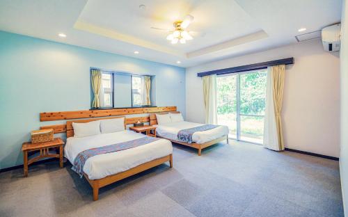 a bedroom with two beds and a large window at Scallop Beach Condominium in Onna