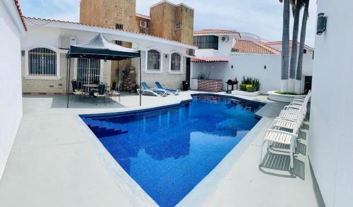 a swimming pool with chairs next to a house at Casa Lomas en Zona Dorada, 5 minutos de la playa in Mazatlán