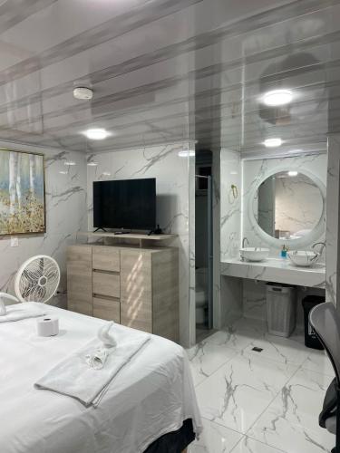 a bedroom with a bed and a tv and a mirror at Hotel Orduz Centro Histórico de Cali in Cali