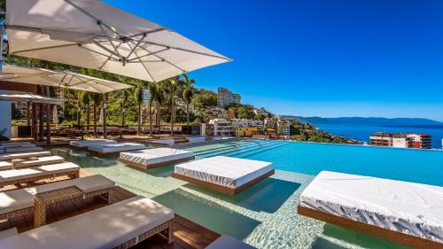 a swimming pool with lounge chairs and umbrellas at SoHo PV - 105 in Puerto Vallarta