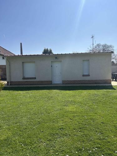 - un bâtiment blanc avec deux fenêtres et une pelouse dans l'établissement Au Petit Faubourg, à Roye