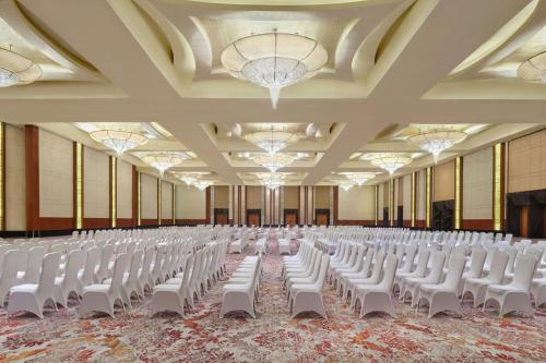 an empty hall with white chairs and chandeliers at The Ritz-Carlton Jakarta, Pacific Place in Jakarta