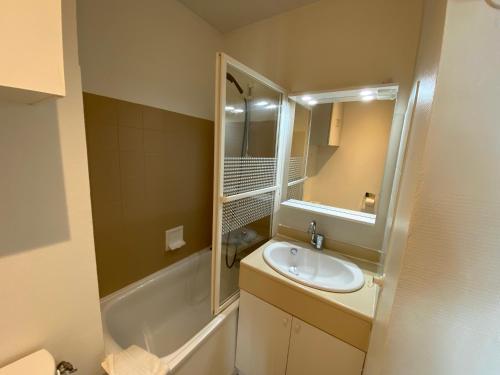 une salle de bain avec un lavabo, un miroir et une baignoire dans l'établissement Appartement face mer Pornichet, à Pornichet