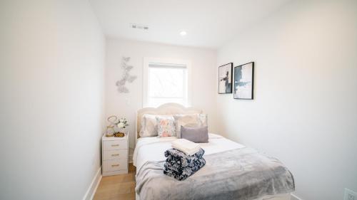 a white bedroom with a bed and a window at Stylish 4BR Home Near Columbia Heights & Rooftop in Washington, D.C.