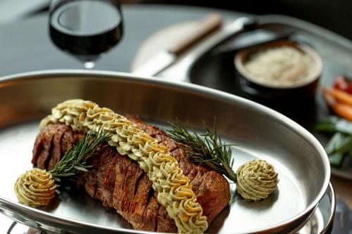a piece of meat in a bowl with rosemary on it at Courtyard by Marriott Biel Bienne in Biel