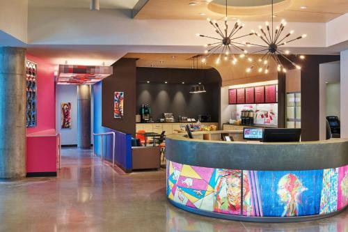 a restaurant lobby with a counter and a kitchen at Aloft Richardson in Richardson
