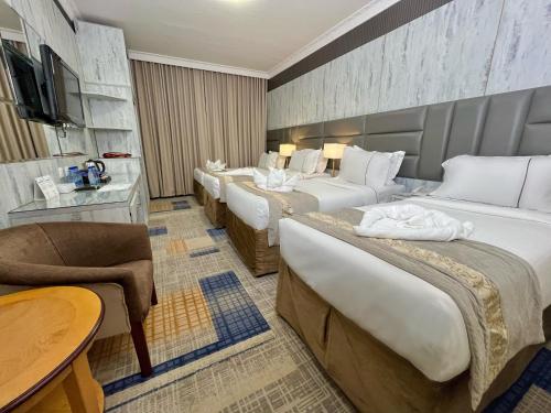 una habitación de hotel con 4 camas y una mesa en Zowar Alalami Hotel, en Medina
