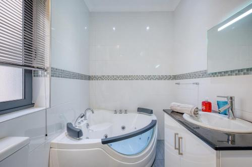 a white bathroom with a tub and a sink at La Casa Provenza in St Paul's Bay