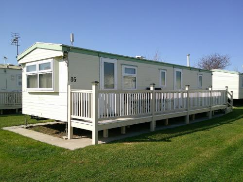 a mobile home with a porch and a fence at Happy Days South Chapel st leonards Sahara 4 Berth in Chapel Saint Leonards
