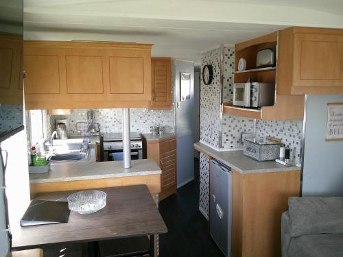 a small kitchen with wooden cabinets and a table at Happy Days South Chapel st leonards Sahara 4 Berth in Chapel Saint Leonards