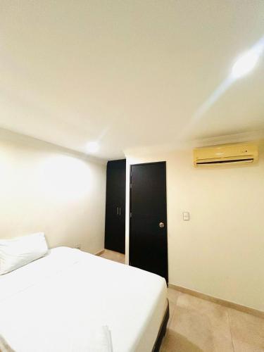 a bedroom with a white bed and a black door at KALINA HOTEL in Girardot