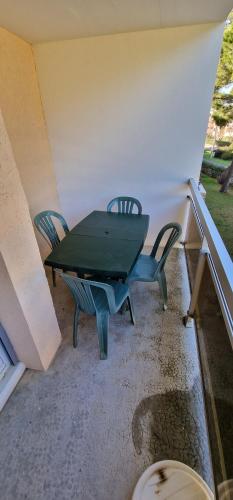 une table et des chaises vertes sur la terrasse dans l'établissement Charmant 28m proche de la mers, à Bormes-les-Mimosas