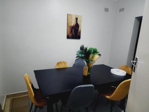 a black dining room table with chairs and a plant at Eastern Road Executive Suites in Harare