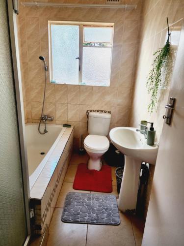 a bathroom with a toilet and a tub and a sink at Eastern Road Executive Suites in Harare