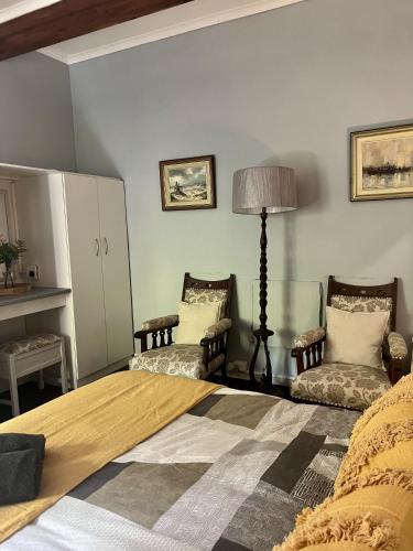 a bedroom with a bed and two chairs and a lamp at Glen House in Brenton-on-Sea