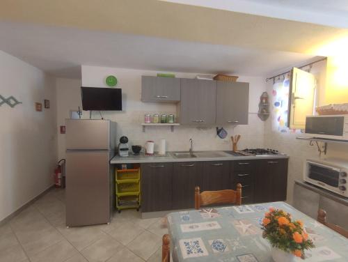 a kitchen with a table and a refrigerator at Appartamento Meduse in Cala Gonone
