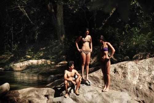 three people in bathing suits standing on rocks near a river at Hotel Hukumeizi Minca in Minca