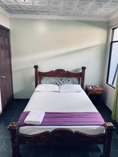 a bedroom with a large bed with white sheets at Hotel el Tucan Alajuela in Alajuela City