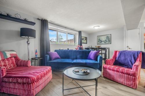 a living room with two blue couches and a table at Modern 3 Bedroom Suite Near Downtown & Stampede Grounds in Calgary