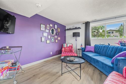 a living room with a blue couch and purple walls at Modern 3 Bedroom Suite Near Downtown & Stampede Grounds in Calgary