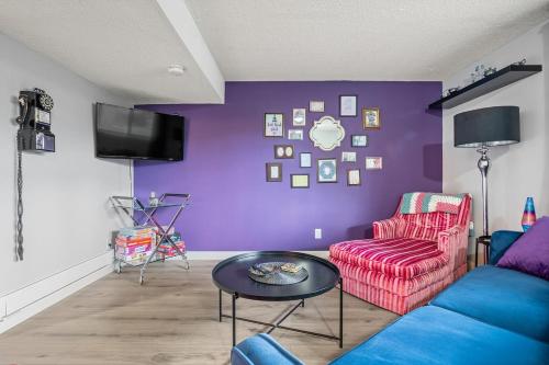 a living room with a couch and a purple wall at Modern 3 Bedroom Suite Near Downtown & Stampede Grounds in Calgary