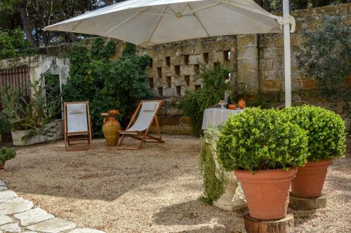 a patio with an umbrella and a table and chairs at Antica Casina B&B di Charme in Pulsano