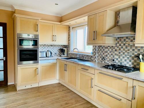 a large kitchen with wooden cabinets and appliances at Home like 3 bed house Sheffield in Sheffield