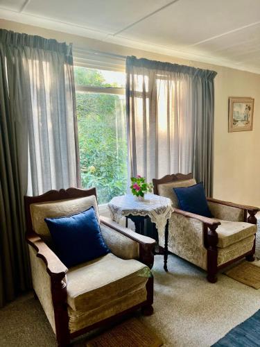 a living room with two chairs and a table and a window at Glen House in Brenton-on-Sea