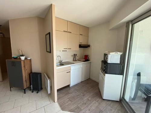 une petite cuisine avec un réfrigérateur et un micro-ondes dans l'établissement Appartement face mer Pornichet, à Pornichet