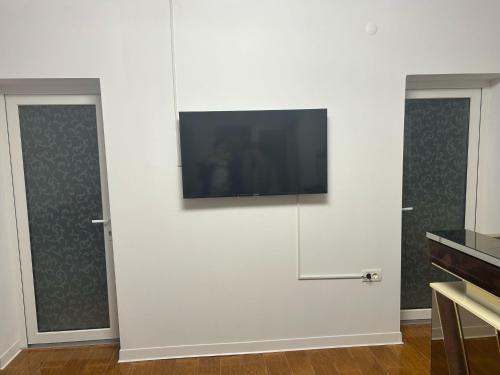 a flat screen tv on a white wall with two doors at Casa de vacanta in Geoagiu Băi
