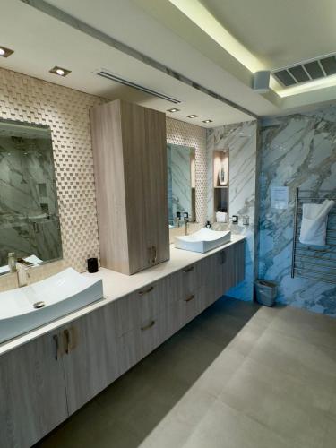 a bathroom with two sinks and two mirrors at Shangri-LA luxury Mansion, Heated Pool in Puerto Peñasco