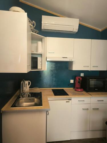 une cuisine avec des armoires blanches et un évier dans l'établissement Logement 2 personnes, à Morières-lès-Avignon