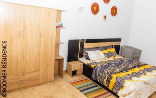 a bedroom with a bed and a wooden cabinet at Boomer Résidence in Abomey-Calavi