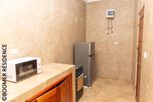 a kitchen with a microwave and a refrigerator at Boomer Résidence in Abomey-Calavi