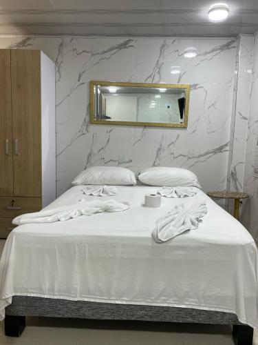 a bedroom with a white bed with a mirror at Hotel Orduz Centro Histórico de Cali in Cali