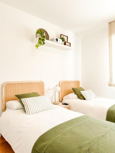 two beds in a room with white walls at Apartamento Nautilus by ALÔGA in Fisterra
