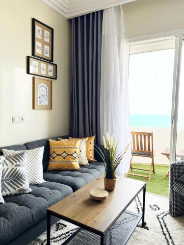 a living room with a blue couch and a table at Ocean view & sunset in the heart of Rabat 2 in Rabat