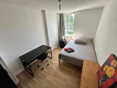una camera con letto e scrivania accanto a una finestra di Renovu Houses in East London a Londra