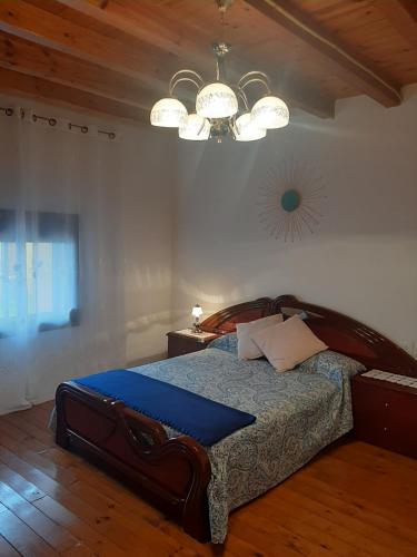 a bedroom with a large wooden bed with a chandelier at Casa Valeriana Guijosa in Guijosa