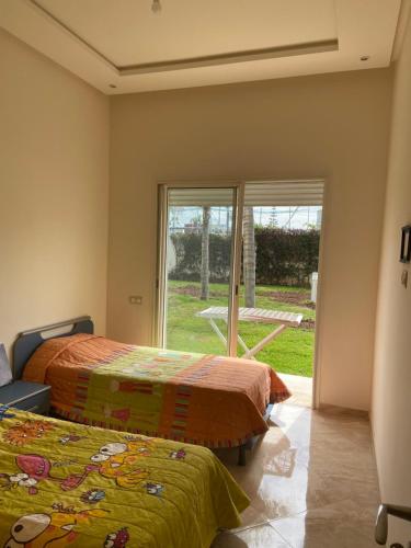 two beds in a room with a window at CASABAY Sidi Rahal, appartement avec accès direct à la piscine in Sidi Rahal