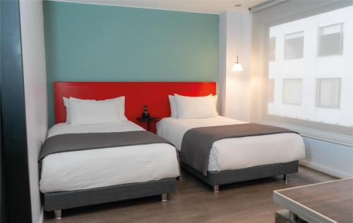 two beds in a room with red and blue walls at Central Apartamentos Bogotá in Bogotá