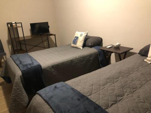 a room with two beds and a table with a television at LiV109 Norte Depa 3 in Cd Obregon in Ciudad Obregón