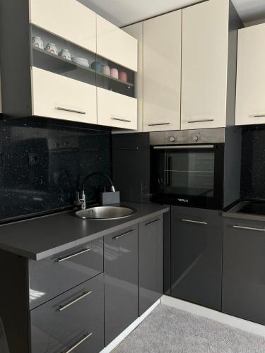 a kitchen with black and white cabinets and a sink at Apartman Eterna in Bijeljina