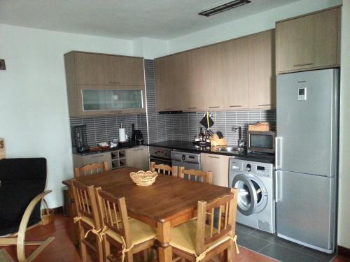 a kitchen with a wooden table and a refrigerator at Armador Apartment in Armação de Pêra