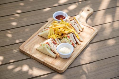 a wooden cutting board with sandwiches and french fries at Oasis Dhigurah in Dhigurah