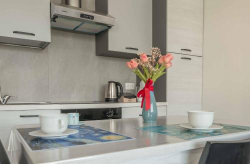 a kitchen counter with two plates and a vase of flowers at Einstein - Modern Apartment with Balcony in Somma Lombardo