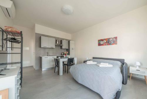 a bedroom with a bed and a table and a kitchen at Einstein - Modern Apartment with Balcony in Somma Lombardo