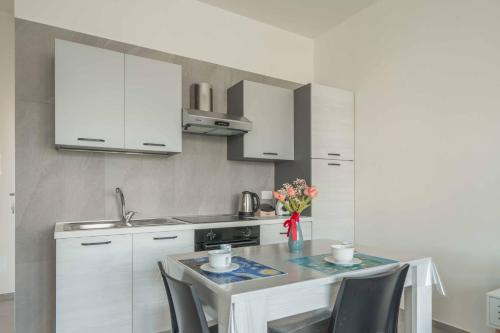 a kitchen with white cabinets and a table with chairs at Einstein - Modern Apartment with Balcony in Somma Lombardo