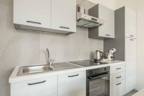 a kitchen with white cabinets and a sink at Einstein - Modern Apartment with Balcony in Somma Lombardo